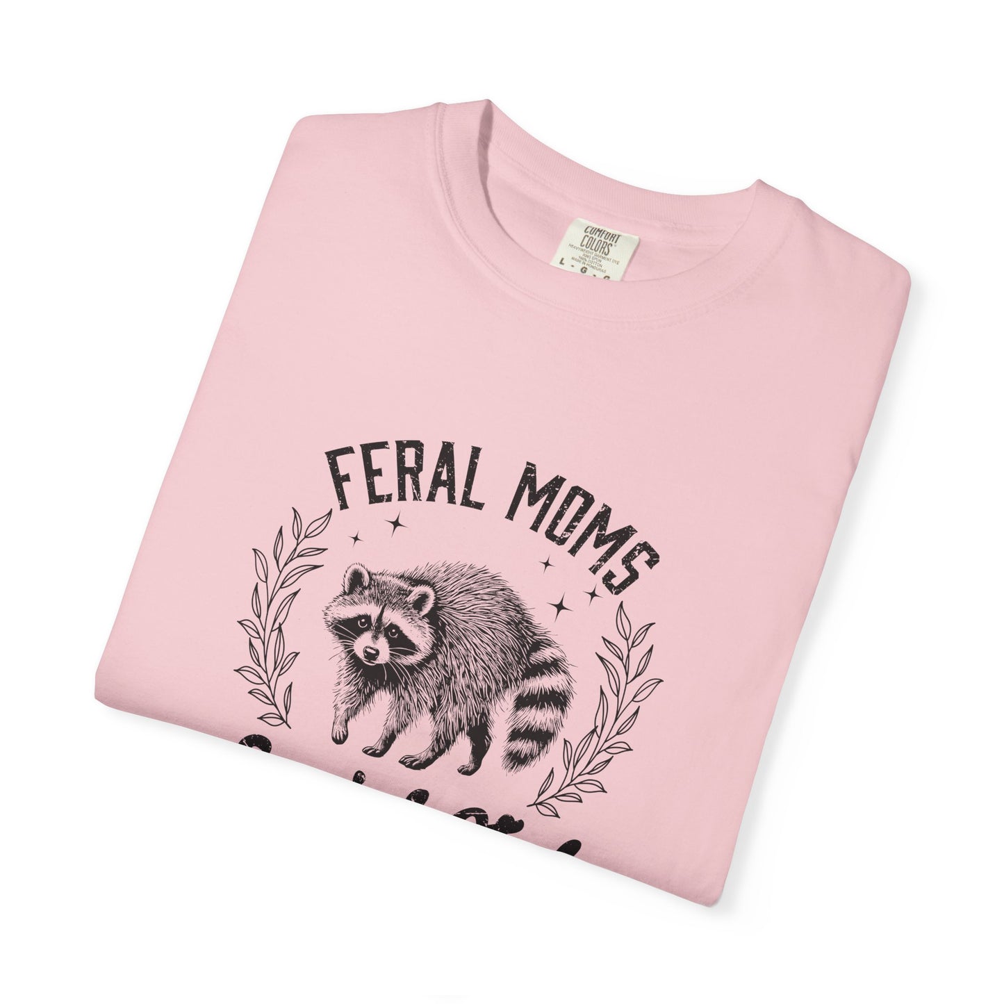 Pink t-shirt with raccoon graphic and 'Feral Moms' text on a white background