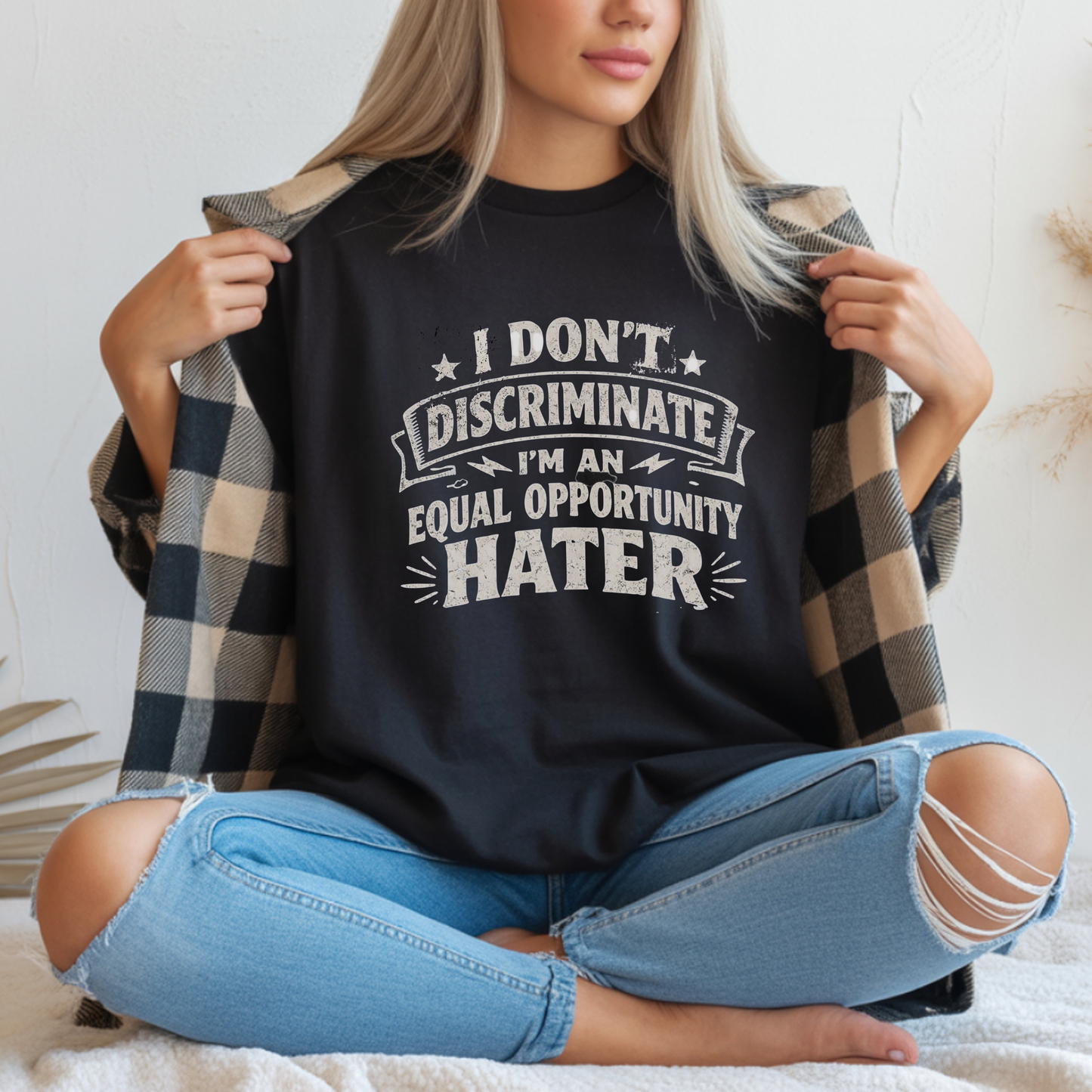 Person wearing a black t-shirt with a humorous text design, sitting on a light-colored surface.