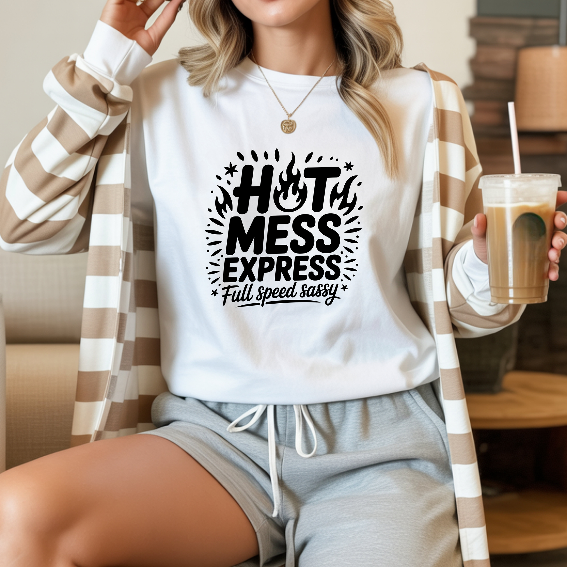 Person wearing a white sweatshirt with 'Hot Mess Express' text, holding a drink.